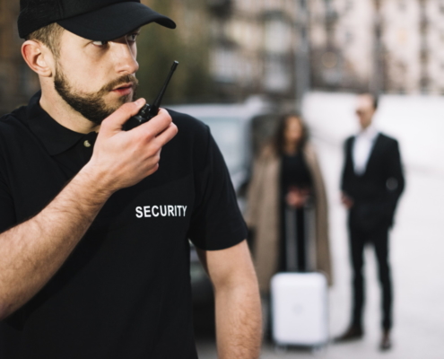 Addetto alla sicurezza in divisa nera con scritta Security parla in ricetrasmittente durante servizio all'aperto