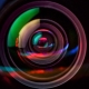 Primo piano macro di un obiettivo fotografico con riflessi rossi e blu, simbolo di bonifica e controllo ambientale
