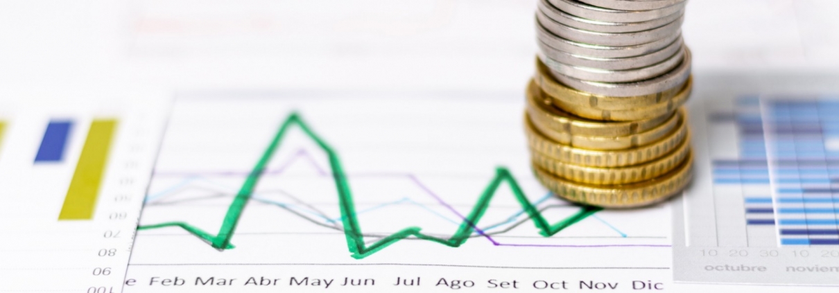Pila di monete su grafici finanziari e tabelle di analisi economica per indagini patrimoniali